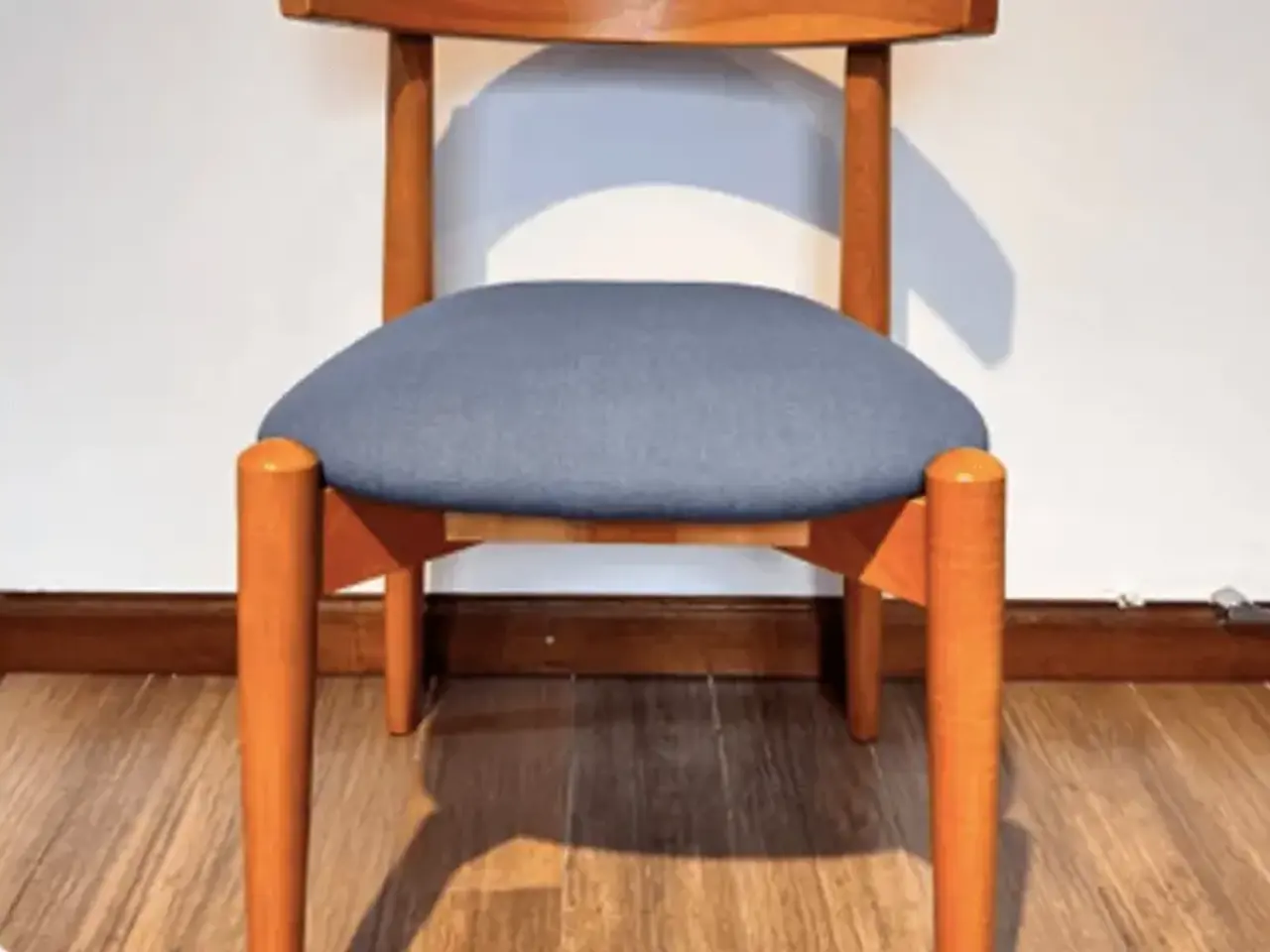 Silla de madera clara con el asiento tapizado en tela azul grisácea
