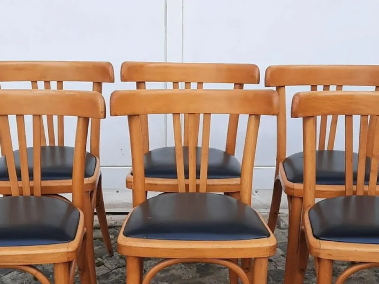 Fila de sillas de madera curvada con los asientos tapizados en cuerina negra
