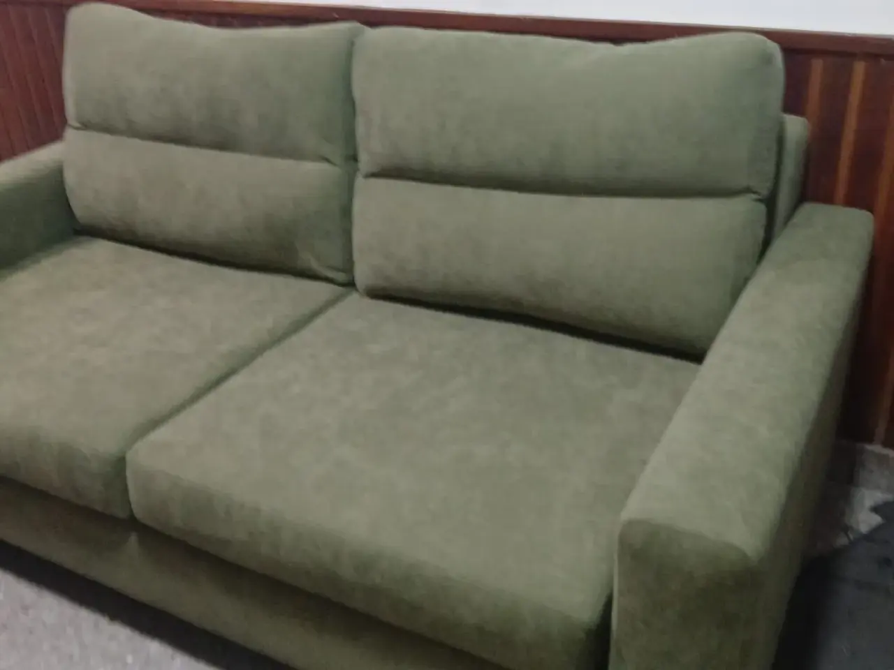 Sofá de dos cuerpos tapizado en tela verde salvia con almohadones al tono